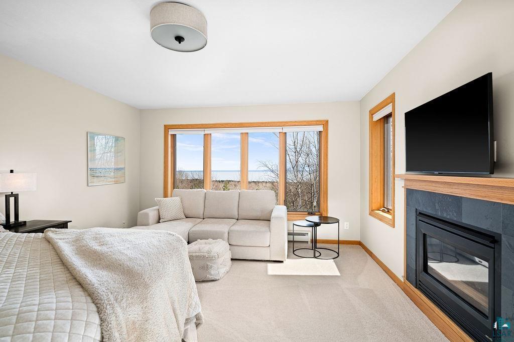 4856 Kingston Street Duluth, MN 55804 - Photo 30 of 88 Carpeted room featuring a large window with natural wood trim, slate tile fireplace surround, natural wood mantel, and ceiling-mounted light fixture