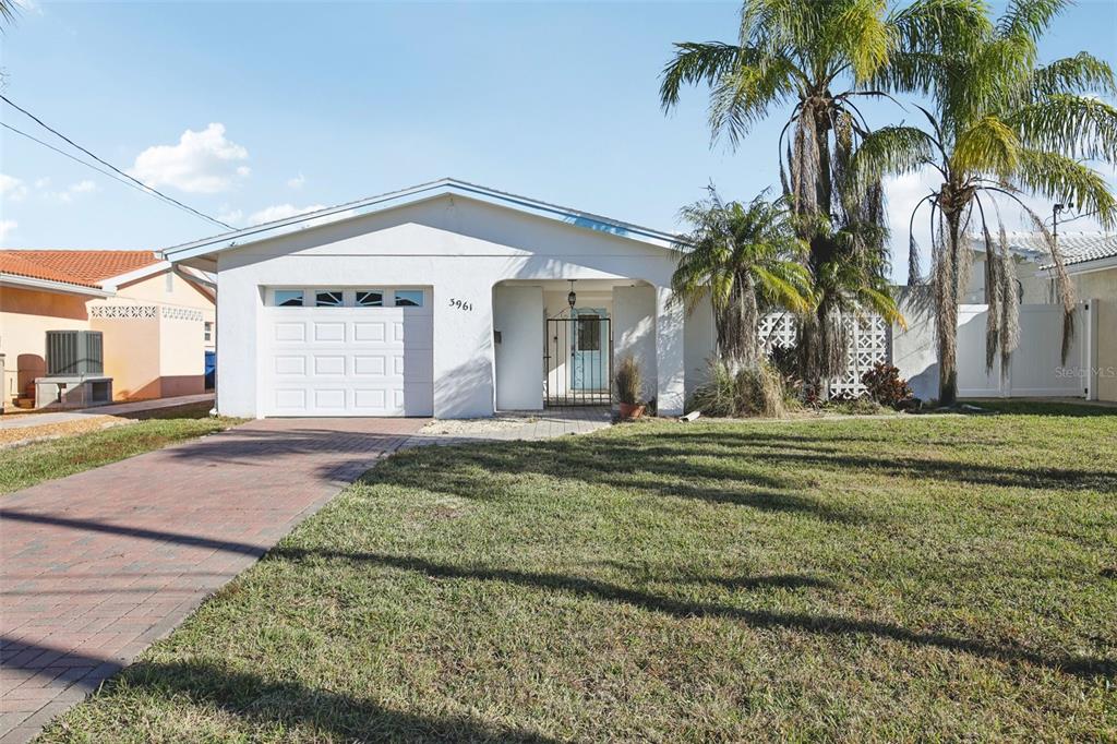 a view of a house with a yard and palm trees