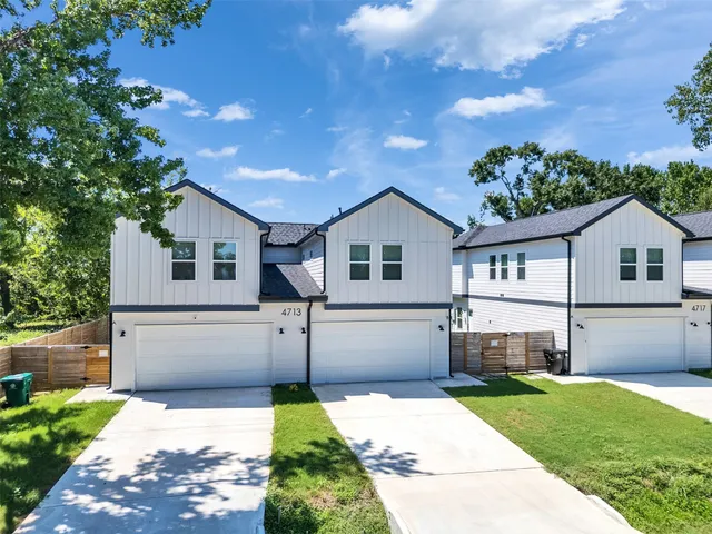 an aerial view of residential houses with outdoor space and trees