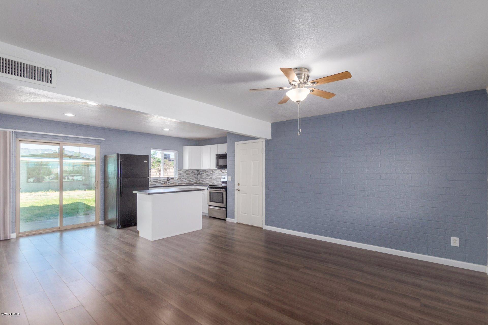 1837 West Vineyard Road Phoenix, AZ 85041 - Photo 5 of 30 a view of an empty room with window and wooden floor