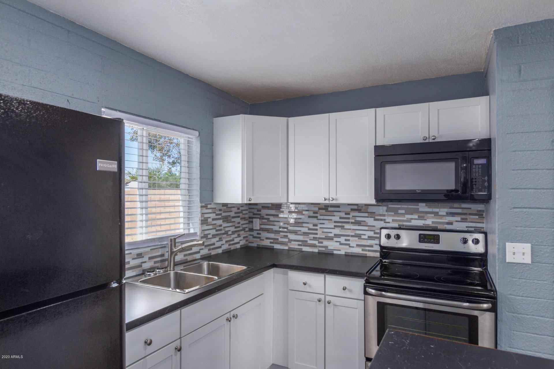 1837 West Vineyard Road Phoenix, AZ 85041 - Photo 8 of 30 a kitchen with sink a microwave a stove and cabinets