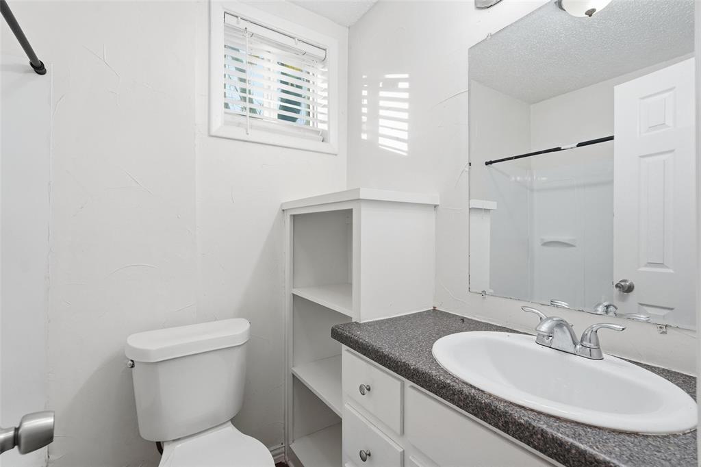 900 West Morgan Street Denison, TX 75020 - Photo 14 of 40 a bathroom with a granite countertop toilet sink and mirror