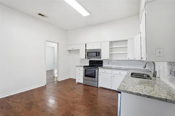 a kitchen with granite countertop white cabinets and stainless steel appliances