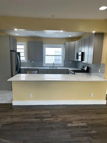 a view of a kitchen with kitchen island a sink wooden floor and a fireplace