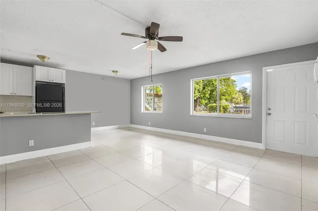 a view of an empty room with a window and a kitchen