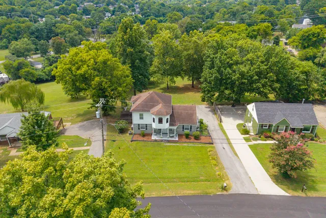 an aerial view of a house with swimming pool and large trees