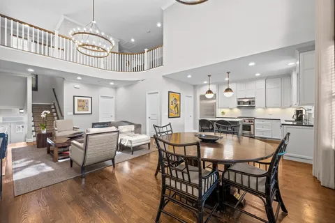 a dining room with wooden floor a chandelier a wooden table and chairs