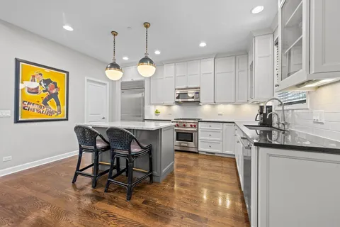 a kitchen with stainless steel appliances granite countertop a sink a stove a refrigerator cabinets and a dining table