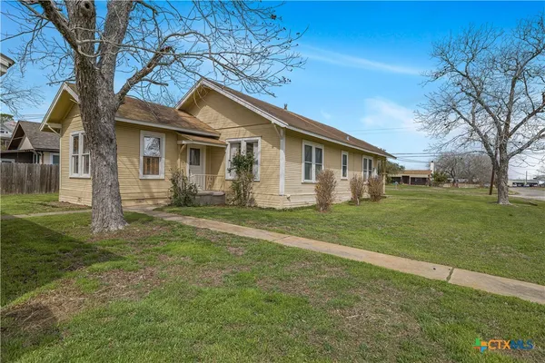 a view of a house with a big yard and large tree