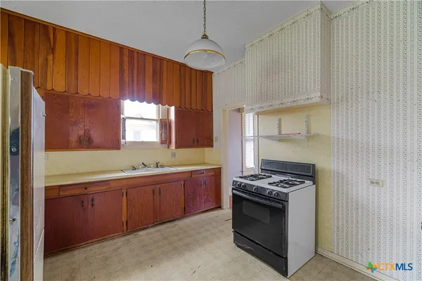 a kitchen with stainless steel appliances a stove a sink cabinets and a window