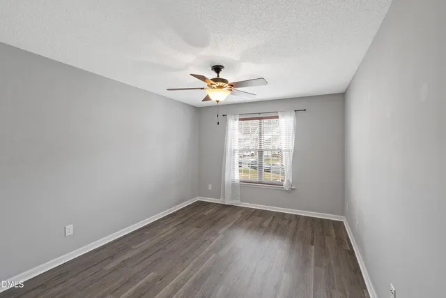 an empty room with wooden floor and ceiling fan