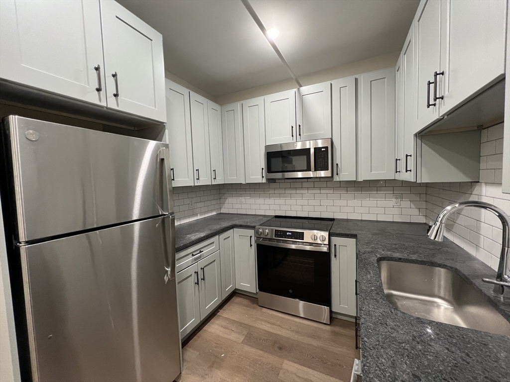 a kitchen with refrigerator a microwave a sink and cabinets
