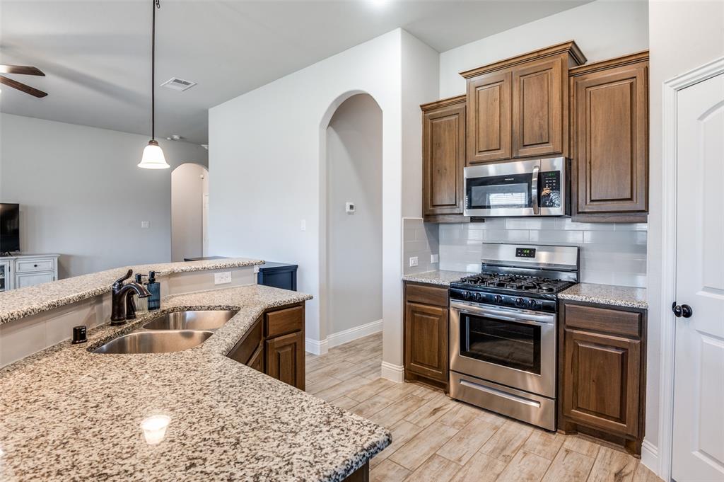 3011 Razorback Street Melissa, TX 75454 - Photo 9 of 25 a kitchen with stainless steel appliances granite countertop a stove a sink and a microwave