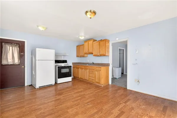 a view of an empty room with a window and kitchen view