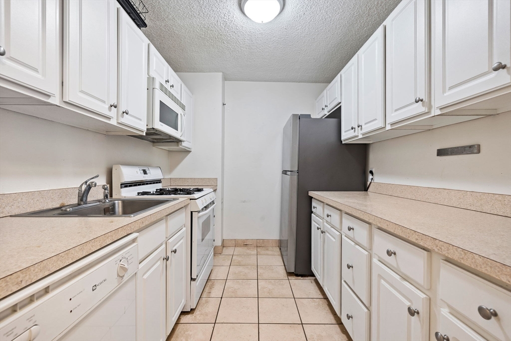 33 Pond Avenue, Unit 704 Brookline, MA 02445 - Photo 3 of 7 a kitchen with granite countertop a sink and cabinets