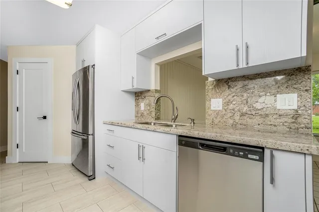 a kitchen with stainless steel appliances granite countertop a sink and a refrigerator
