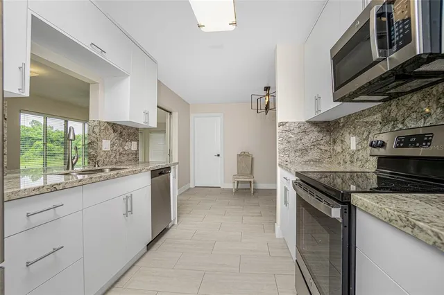 a kitchen with stainless steel appliances granite countertop a stove a sink and a microwave