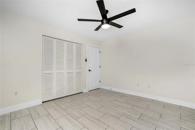 an empty room with a ceiling fan and window