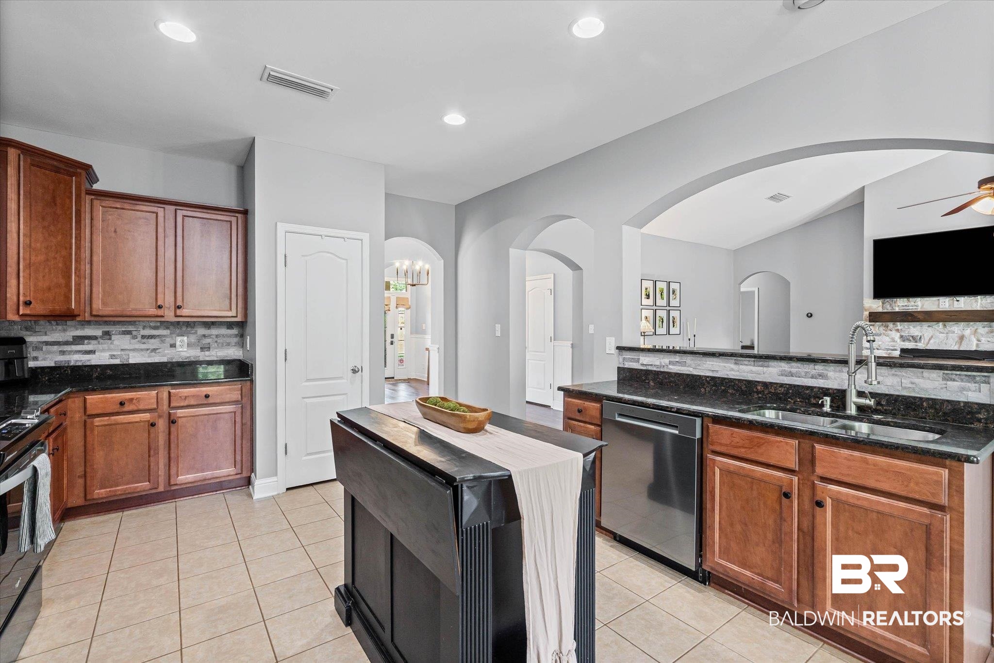 3739 Whitestone Drive Semmes, AL 36575 - Photo 10 of 25 Kitchen featuring warm wood cabinetry, dark speckled countertops, and a mosaic tile backsplash