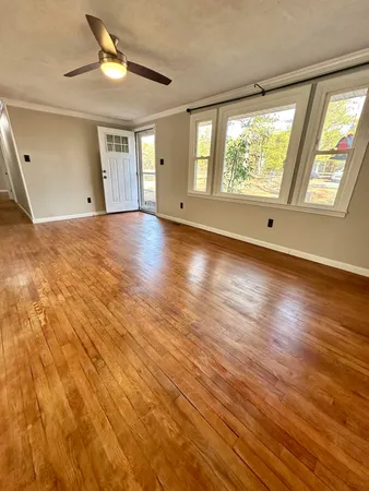 a view of an empty room with wooden floor and a window