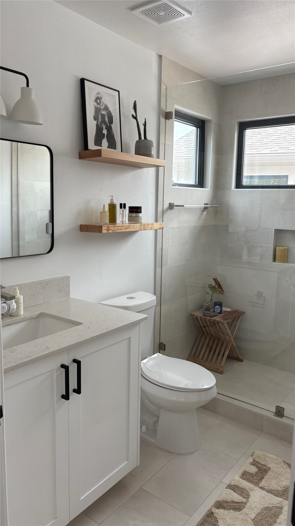 1816 Adina Street, Unit 2 Austin, TX 78721 - Photo 14 of 25 Contemporary bathroom featuring a spacious glass-enclosed shower with tile surround, white vanity with stone-look countertop, rectangular undermount sink, and black hardware