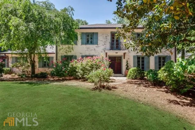 a front view of a house with a garden and trees