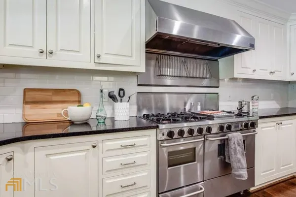 a kitchen with stainless steel appliances granite countertop white cabinets and a stove top oven