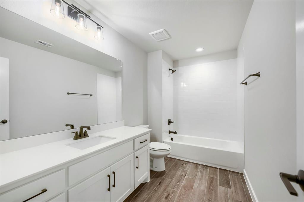 800 Blackberry Road Haslet, TX 76052 - Photo 23 of 28 Bathroom featuring a white vanity with integrated sink, white cabinetry, dark bronze hardware, and wood-finish flooring