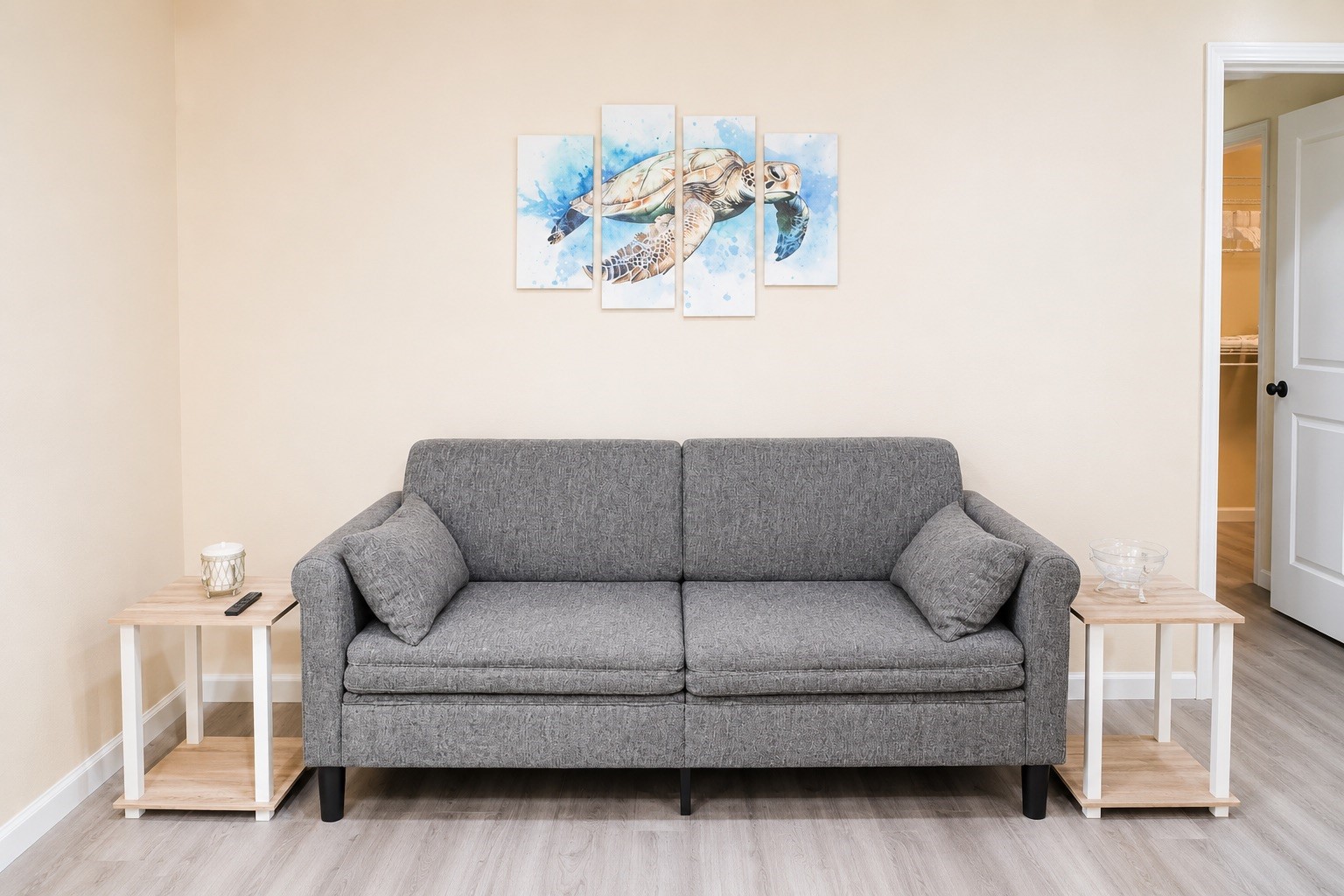 Cozy living space featuring a stylish gray sofa with matching side tables, complemented by serene wall art, perfect for relaxation.