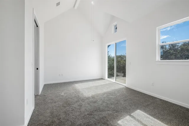 a view of an empty room with wooden floor and a bathroom