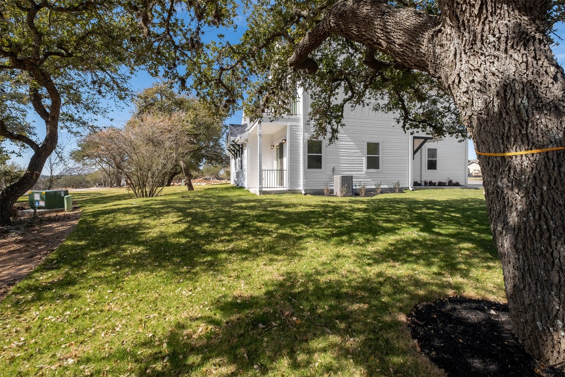 255 Lourdes Court, Unit A Dripping Springs, TX 78620 - Photo 27 of 27 a big white house with a yard and large trees