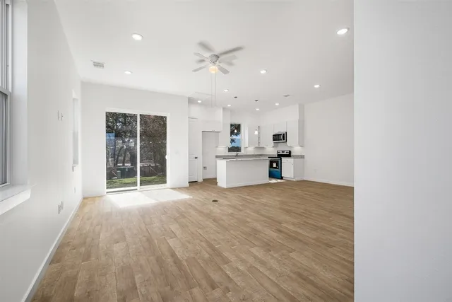 a view of an empty room with wooden floor and stairs