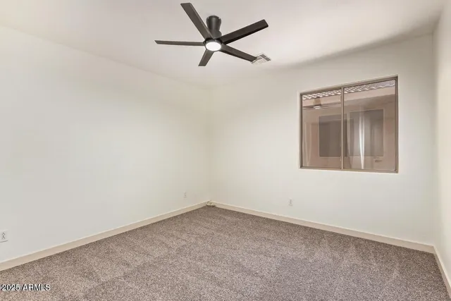 an empty room with a window and a fan