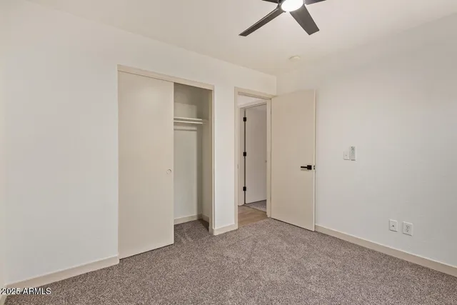 an empty room with a ceiling fan and carpet