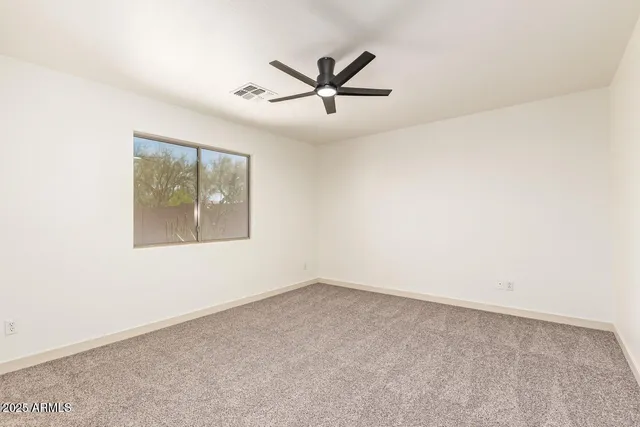 an empty room with window and ceiling fan