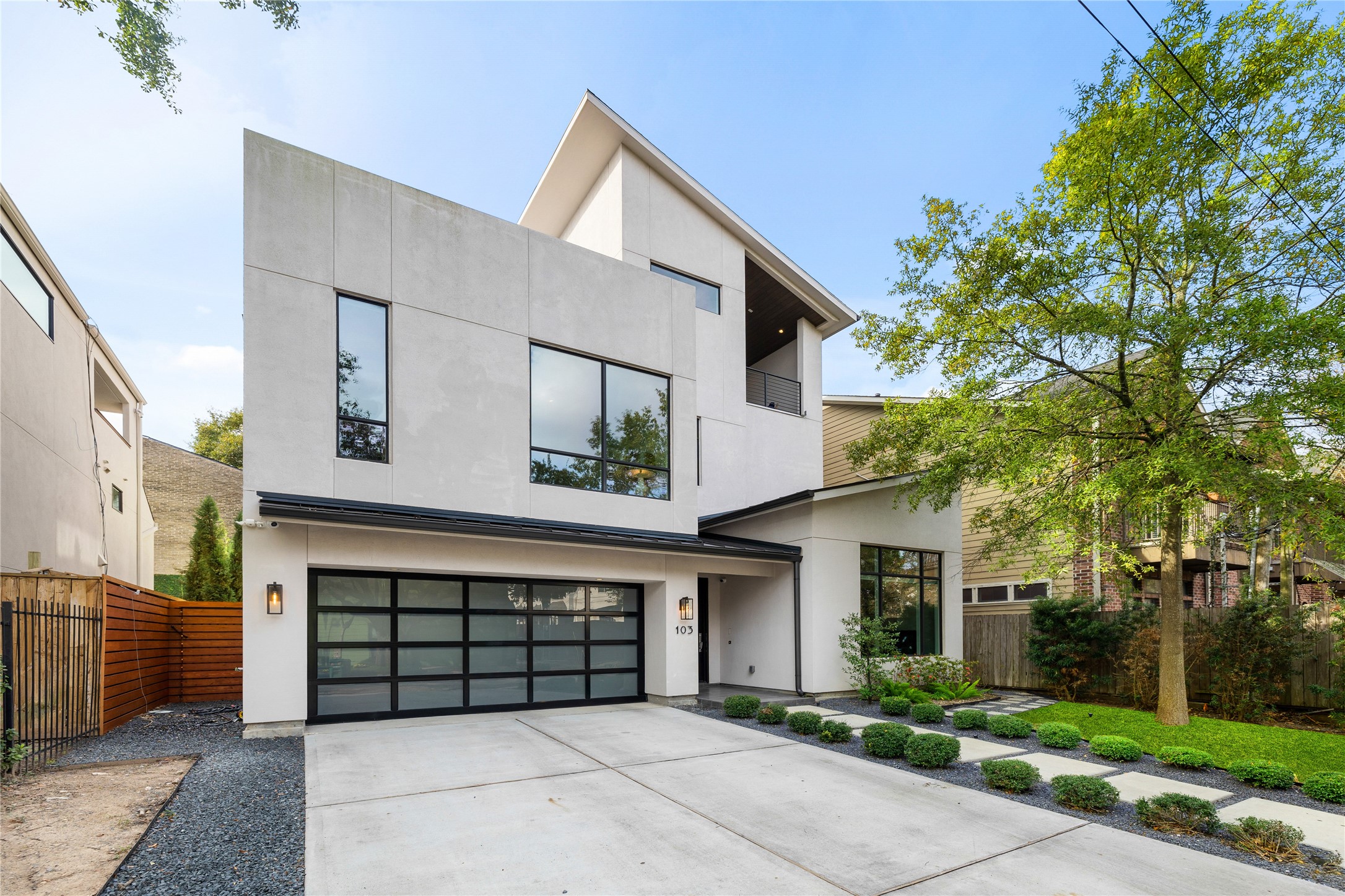 Clean contemporary façade defined by strong geometry, expansive windows, and a refined material palette. The three-level composition balances privacy with natural light, complemented by a modern glass-paneled garage door and minimalist landscape approach that reinforces the home’s architectural presence.