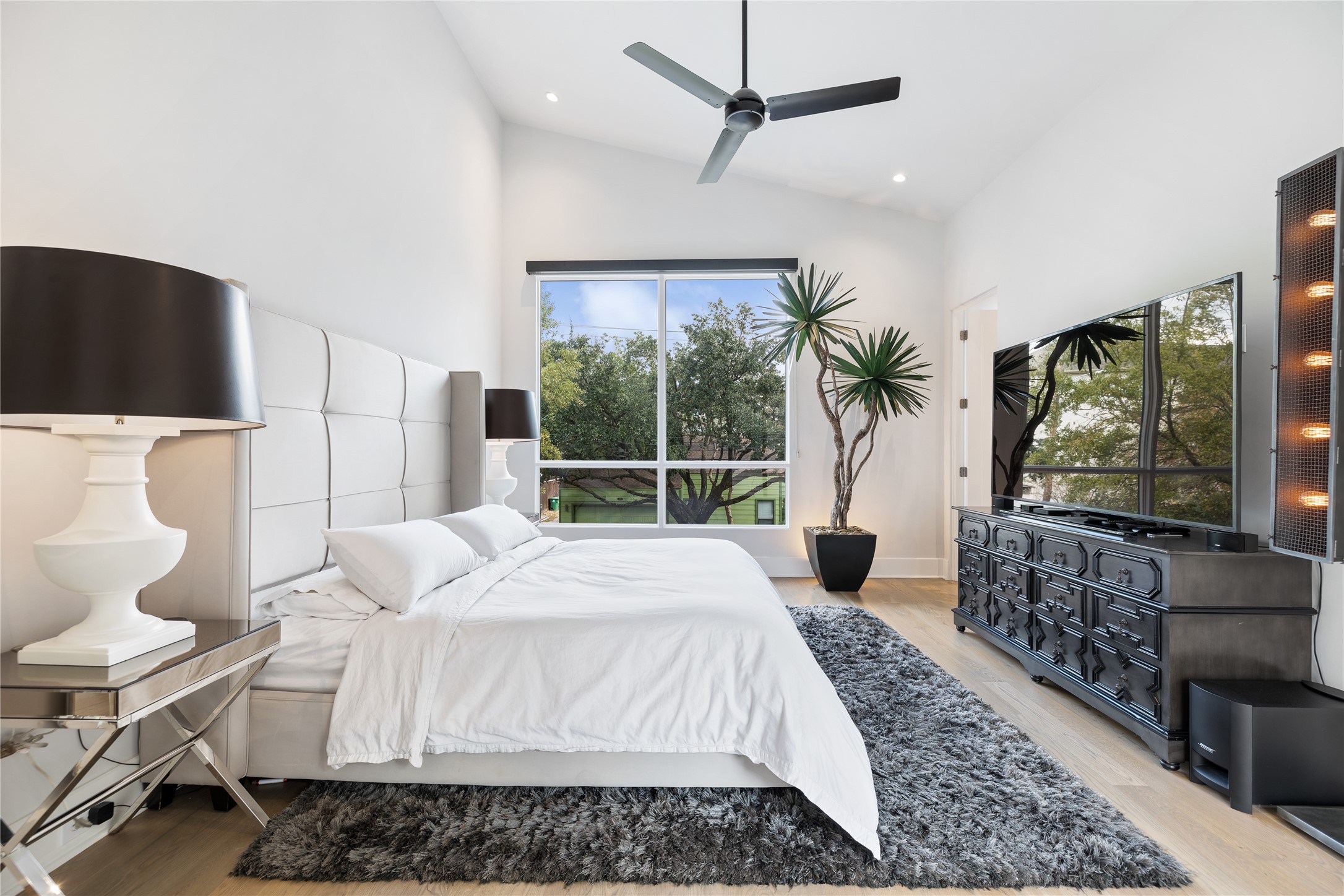 103 Roy Street Houston, TX 77007 - Photo 26 of 37 Light-filled secondary bedroom featuring soaring ceilings, expansive picture window, and ample space for a king-size bed and lounge furnishings — offering comfort, style, and versatility for guests or family members.