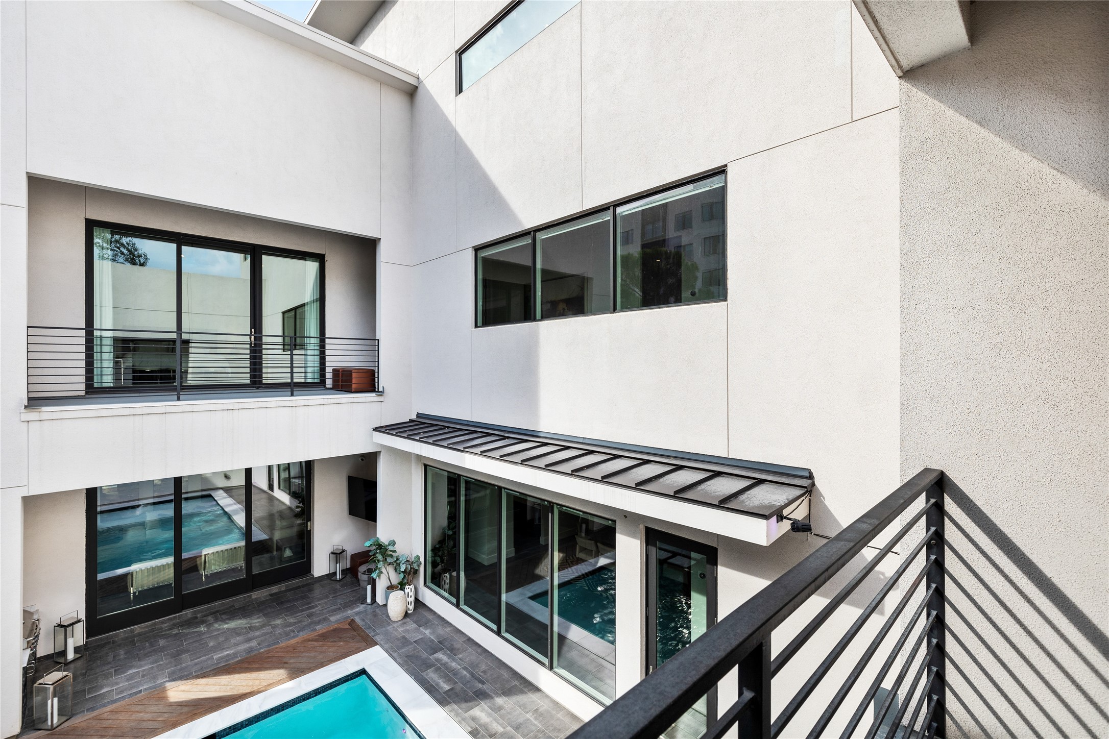 103 Roy Street Houston, TX 77007 - Photo 28 of 37 Striking multi-level architecture surrounds a private interior courtyard, where expansive windows and balcony vantage points from the second bedroom overlook the pool below, creating a dramatic blend of natural light, clean lines, and modern design continuity throughout the home.