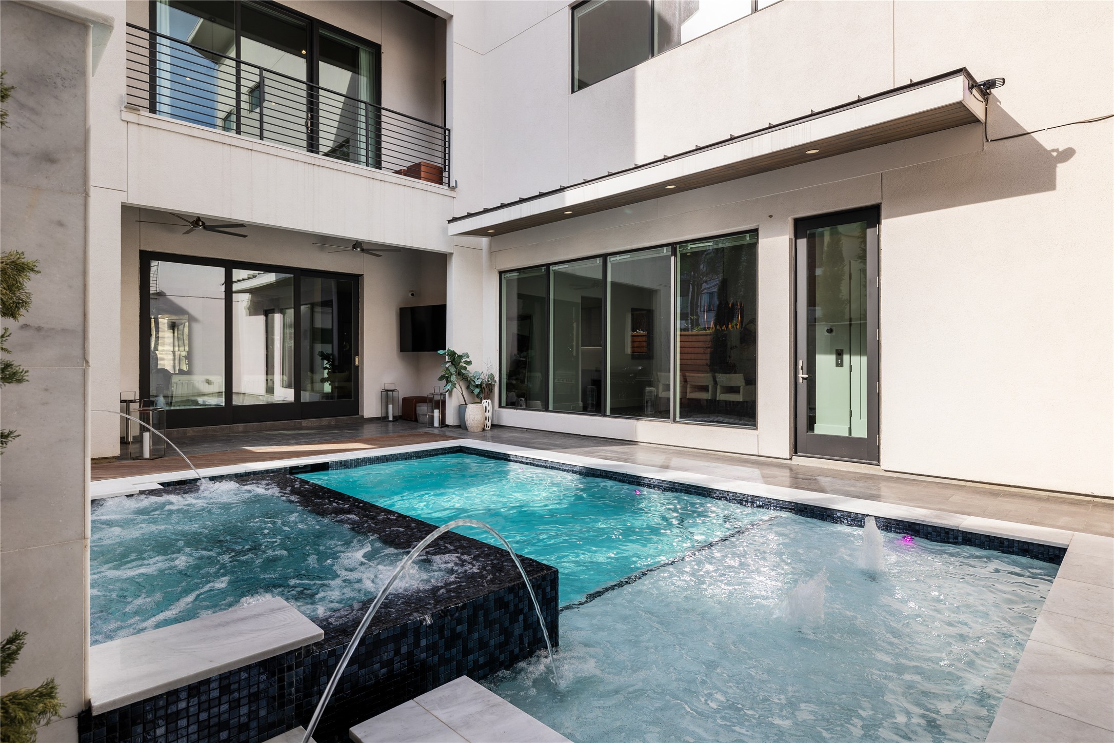 103 Roy Street Houston, TX 77007 - Photo 36 of 37 Private interior courtyard showcases a striking pool and elevated spa with water features, surrounded by floor-to-ceiling glass and modern architectural lines — creating a tranquil, resort-style centerpiece ideal for entertaining and everyday relaxation.