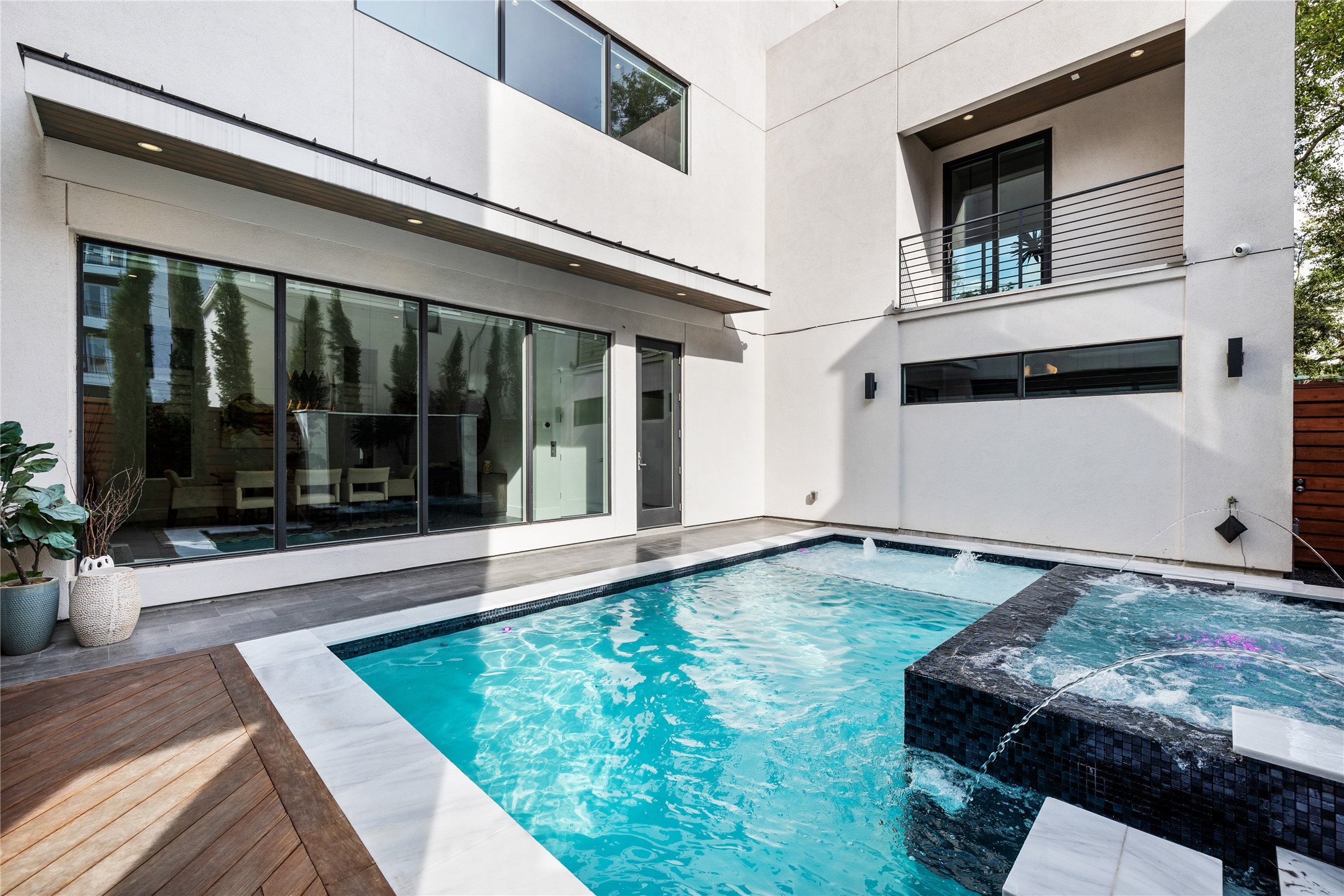 103 Roy Street Houston, TX 77007 - Photo 37 of 37 Striking modern courtyard features a sleek pool and raised spa with cascading water features, framed by expansive glass walls and clean contemporary lines. Seamless indoor-outdoor connectivity enhances natural light while creating a private oasis ideal for entertaining or relaxing in style.