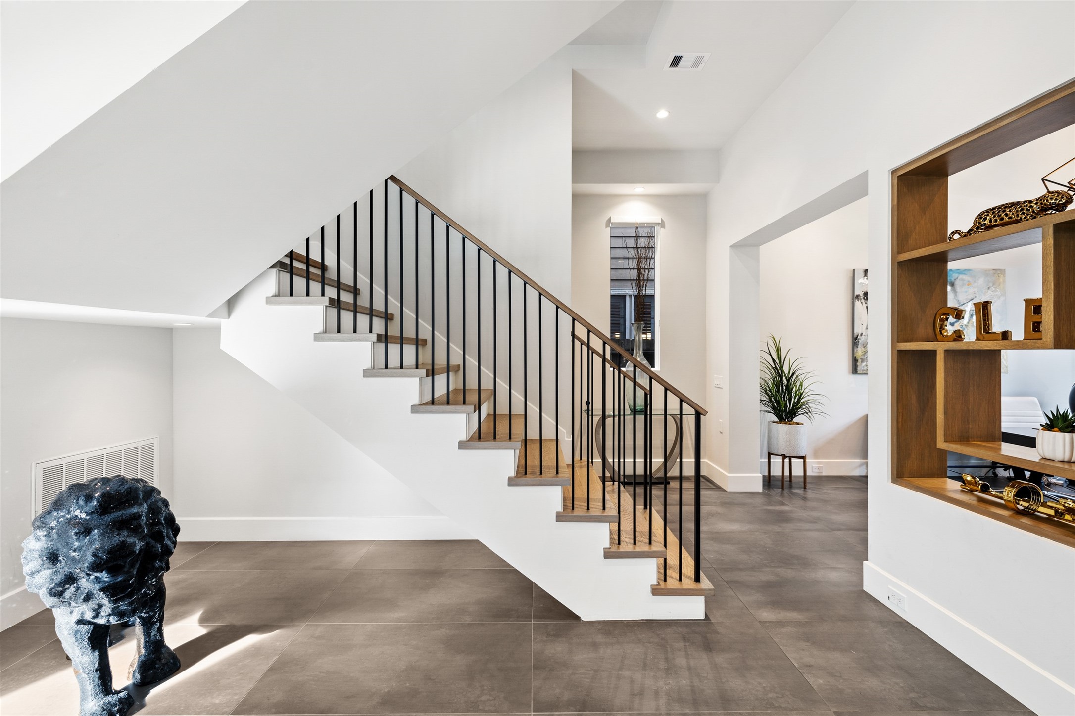 103 Roy Street Houston, TX 77007 - Photo 4 of 37 Floating stair design with warm wood treads and minimalist metal railing creates a striking architectural focal point, enhancing the home’s open layout and modern design continuity.