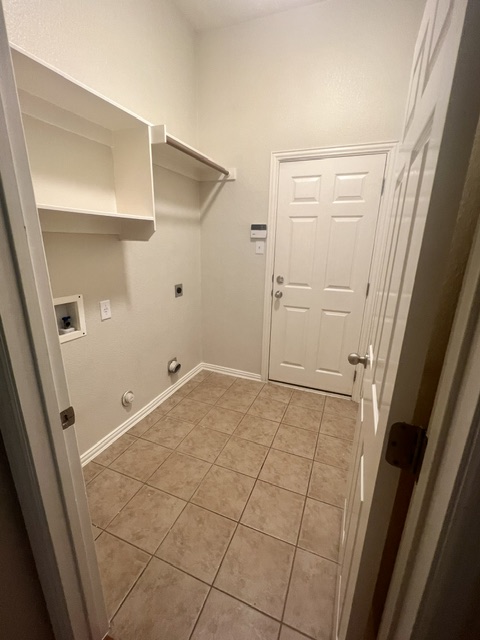 20724 Kearney Hill Road Pflugerville, TX 78660 - Photo 33 of 40 Utility room featuring ceramic tile flooring, built-in shelving, a clothes hanging rod, and a paneled door