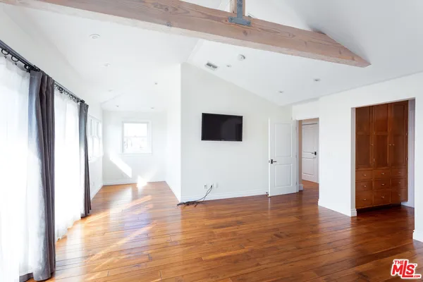 a view of an empty room with wooden floor and windows