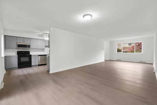 a view of a kitchen with a sink stove cabinets and empty room