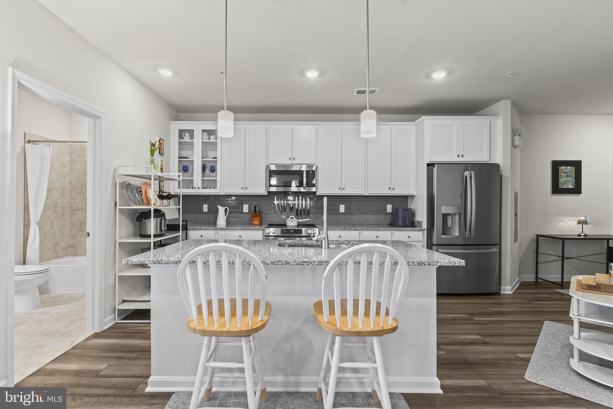 4007 Seaside Alder Road, Unit 8307 Bowie, MD 20720 - Photo 5 of 32 a kitchen with stainless steel appliances granite countertop a dining table chairs refrigerator and microwave