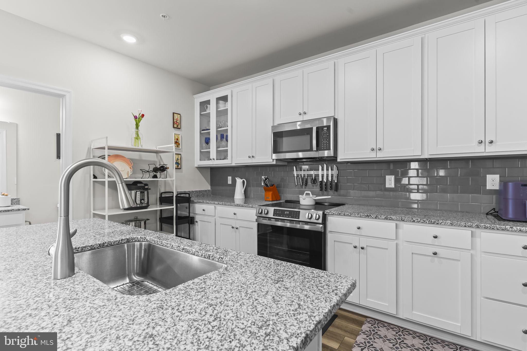 4007 Seaside Alder Road, Unit 8307 Bowie, MD 20720 - Photo 7 of 32 a kitchen with kitchen island granite countertop a sink a stove and cabinets