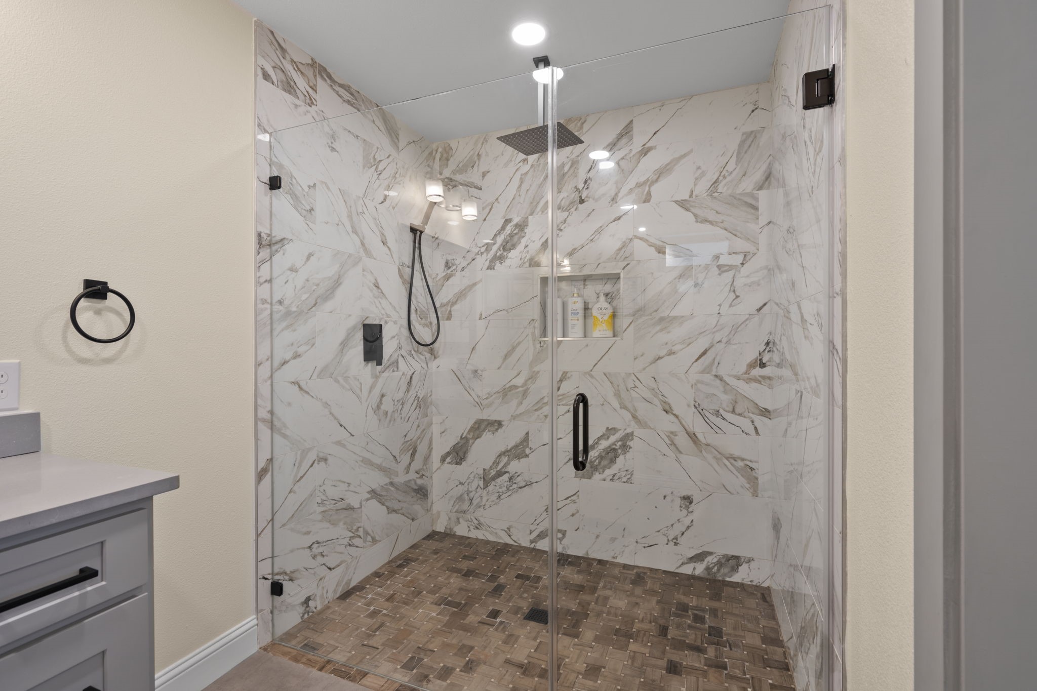 2402 Chimney Rock Road Houston, TX 77057 - Photo 19 of 36 Spa-like walk-in shower with marble-look tile, frameless glass enclosure, rainfall showerhead, and built-in niche—perfect blend of luxury and modern design.
