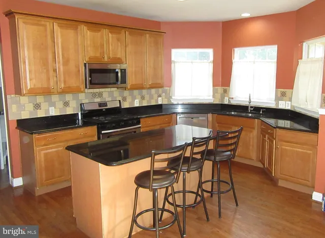 a kitchen with stainless steel appliances granite countertop a sink a stove a microwave a counter space and cabinets