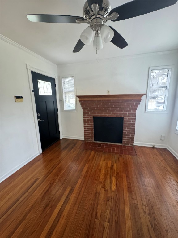 3405 Cherrywood Road Austin, TX 78722 - Photo 3 of 17 Unfurnished living room featuring crown molding, dark wood-type flooring, a brick fireplace, and ceiling fan