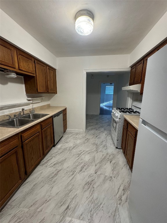 3405 Cherrywood Road Austin, TX 78722 - Photo 4 of 17 Kitchen with white appliances, light countertops, light marble finish floors, under cabinet range hood, and dark brown cabinetry